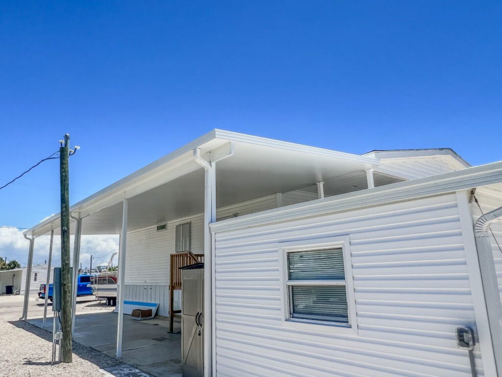 View of a mobile home with a newly constructed metal carport, offering durable protection, installed by a professional carport installation company in Southwest Florida | Sun Control Aluminum & Remodeling